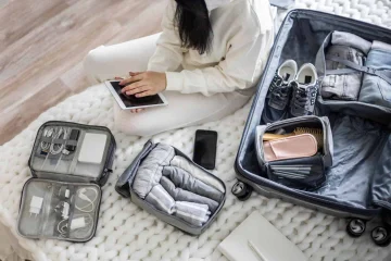 a woman sitting on the floor with a suitcase and a tablet