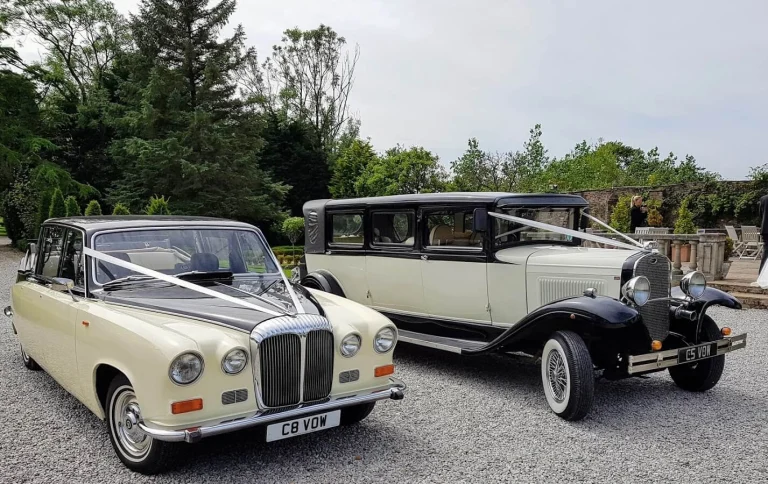 a couple of vintage cars parked in a driveway